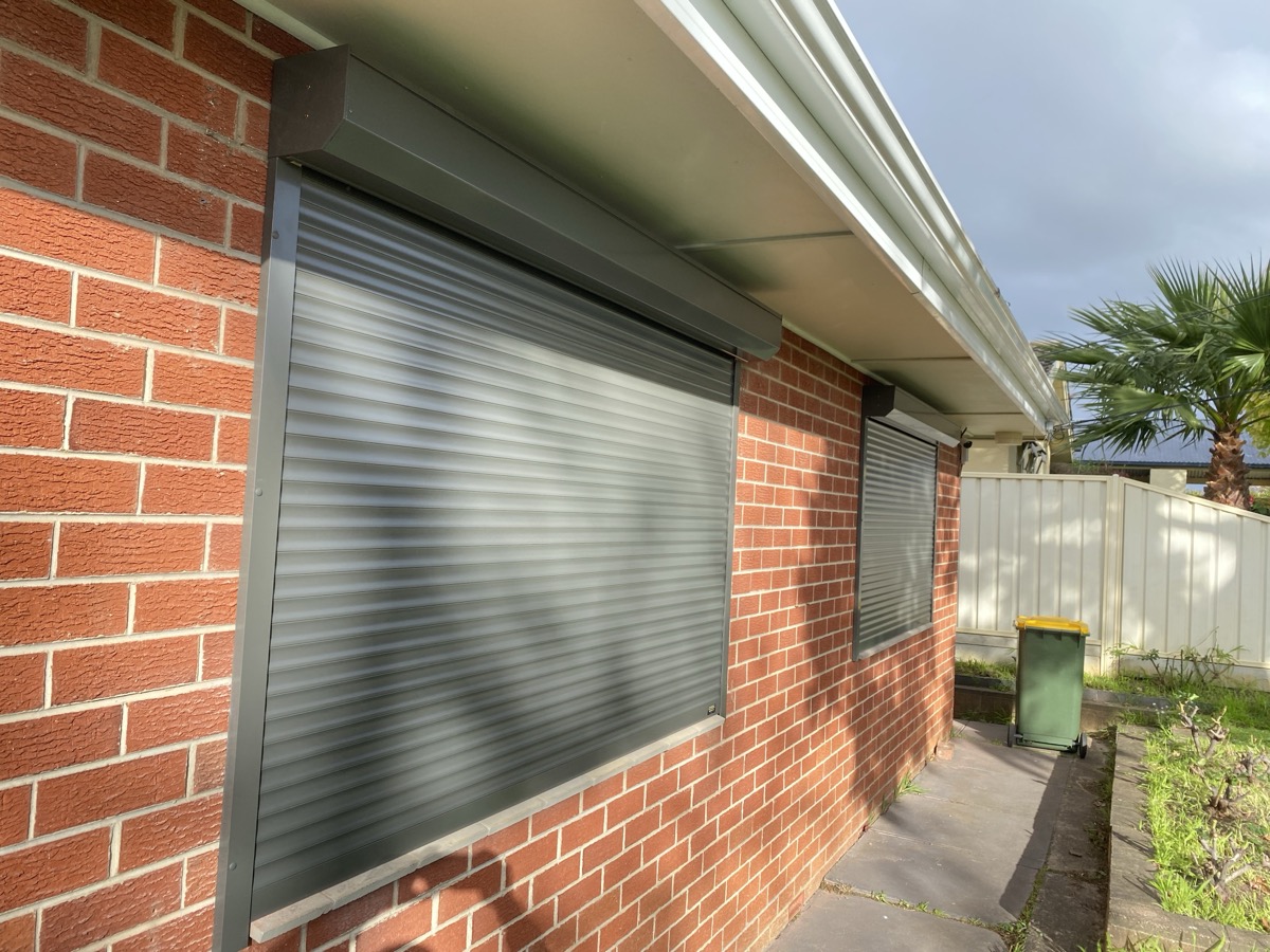 Grey roller shutters red brick side