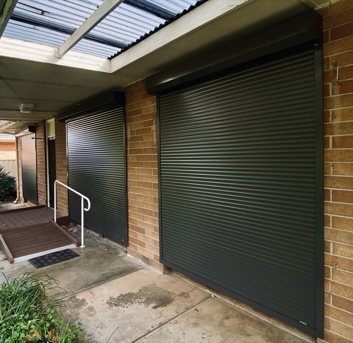 Dark green roller shutters brick